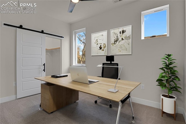 carpeted home office with a barn door, a ceiling fan, and baseboards