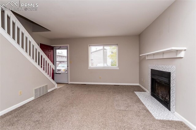 1295 Soaring Eagle Dr, Colorado Springs, CO 80915 - unfurnished living room featuring a tiled fireplace, carpet floors, stairway, and baseboards