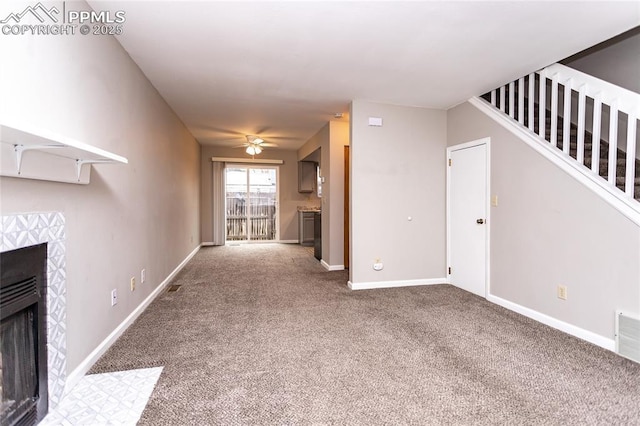1295 Soaring Eagle Dr, Colorado Springs, CO 80915 - unfurnished living room featuring carpet flooring, ceiling fan, a tiled fireplace, stairs, and baseboards
