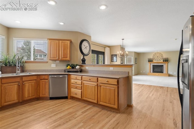 11985 Hanging Valley Way, Colorado Springs, CO 80921 - kitchen featuring stainless steel appliances, a peninsula, light wood finished floors, a fireplace with raised hearth, and recessed lighting