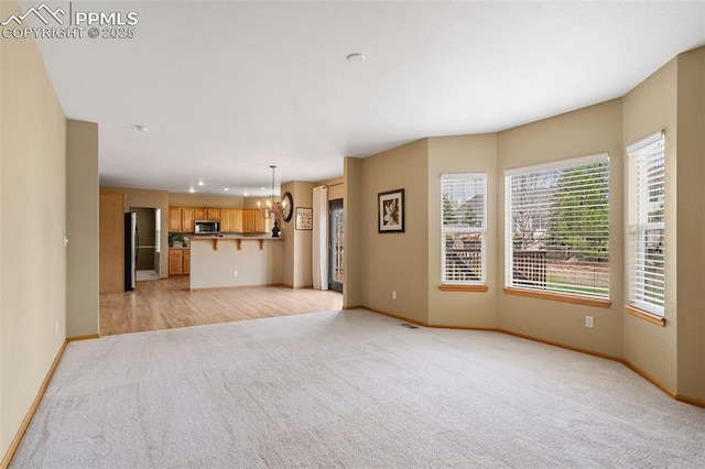 11985 Hanging Valley Way, Colorado Springs, CO 80921 - unfurnished living room with light colored carpet, a chandelier, and baseboards