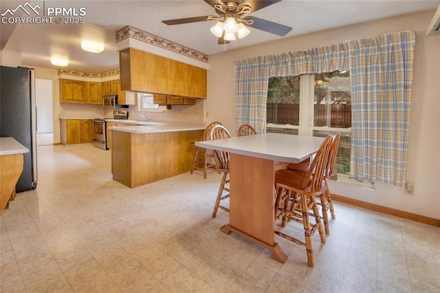 770 Allegheny Dr, Colorado Springs, CO 80919 - kitchen featuring appliances with stainless steel finishes, brown cabinetry, a peninsula, a sink, and light countertops
