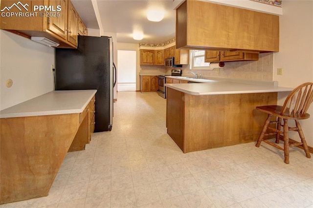 770 Allegheny Dr, Colorado Springs, CO 80919 - kitchen featuring appliances with stainless steel finishes, a peninsula, brown cabinets, light countertops, and a sink
