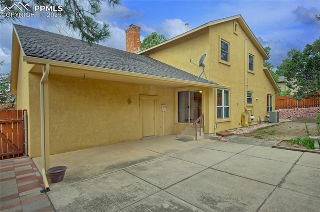 770 Allegheny Dr, Colorado Springs, CO 80919 - back of house with fence, stucco siding, a chimney, central AC, and a shingled roof