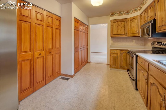 770 Allegheny Dr, Colorado Springs, CO 80919 - kitchen featuring stainless steel appliances, brown cabinetry, light countertops, tasteful backsplash, and baseboards