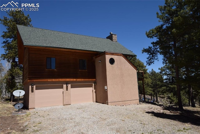 78 Powderhorn Ln, Florissant, CO 80816 - view of home's exterior with a chimney, an attached garage, roof with shingles, gravel driveway, and stucco siding