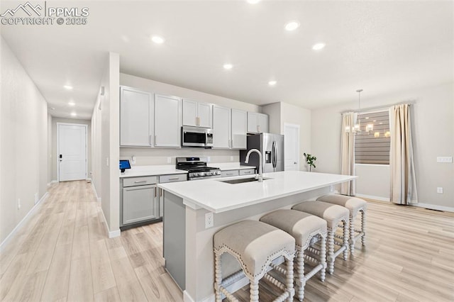 8093 Yellowleaf Pl, Colorado Springs, CO 80908 - kitchen with appliances with stainless steel finishes, a sink, a kitchen breakfast bar, a kitchen island with sink, and light wood-type flooring