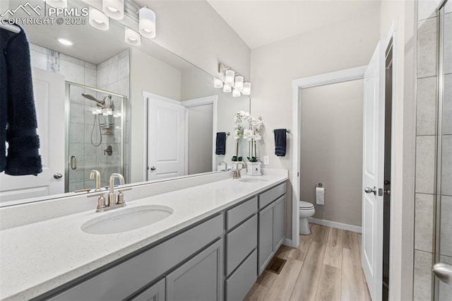 8093 Yellowleaf Pl, Colorado Springs, CO 80908 - full bathroom with double vanity, toilet, wood finished floors, a stall shower, and a sink