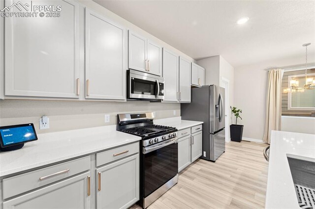 8093 Yellowleaf Pl, Colorado Springs, CO 80908 - kitchen featuring light countertops, light wood-type flooring, stainless steel appliances, and an inviting chandelier