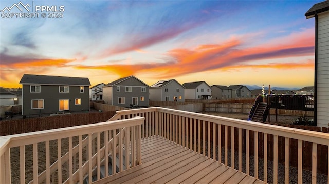 deck at dusk with a fenced backyard and a residential view