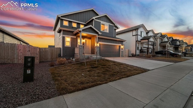 view of front of home with board and batten siding, driveway, fence, an attached garage, and stone siding