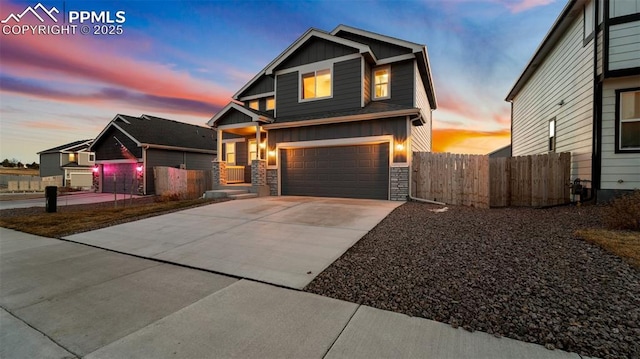 craftsman inspired home featuring fence, stone siding, driveway, a garage, and board and batten siding