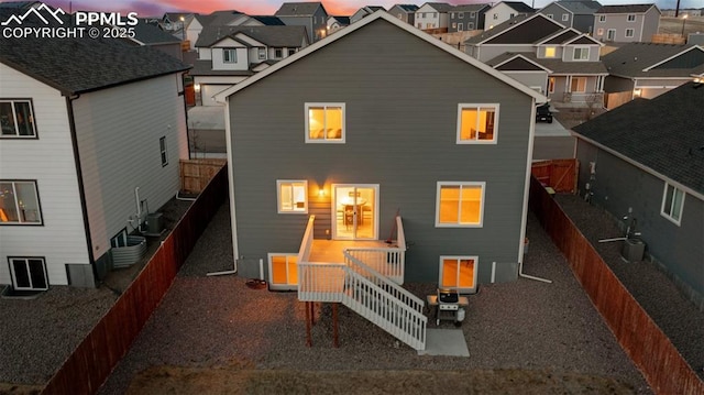 back of house at dusk with central AC unit, a residential view, and a fenced backyard