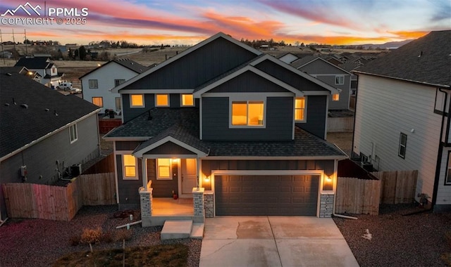 view of front of property with board and batten siding, a shingled roof, an attached garage, and fence