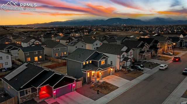 aerial view at dusk featuring a mountain view and a residential view