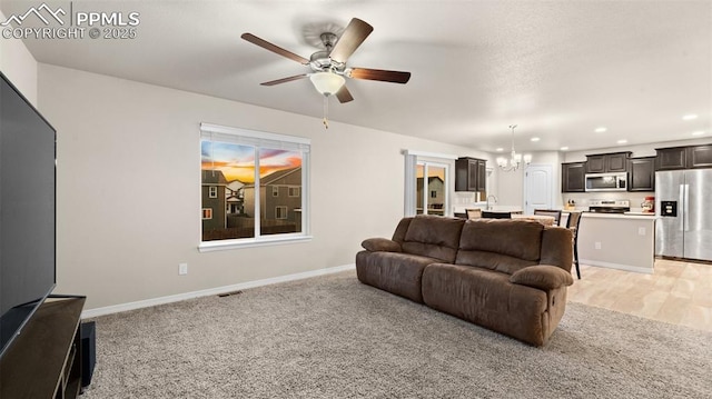 living room with ceiling fan with notable chandelier, visible vents, baseboards, light carpet, and recessed lighting