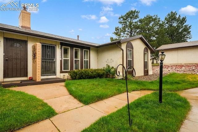 3314 Valley Hi Ave Unit B, Colorado Springs, CO 80910 - view of front facade with stucco siding, a front yard, and a chimney