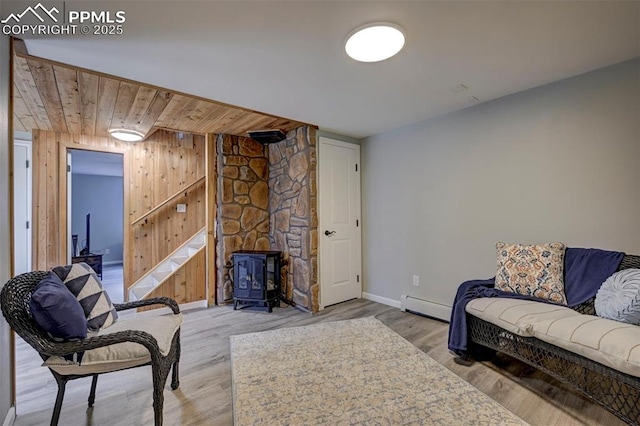 3645 Doolittle Rd, Monument, CO 80132 - sitting room with a baseboard radiator, a wood stove, baseboards, wood finished floors, and wooden walls
