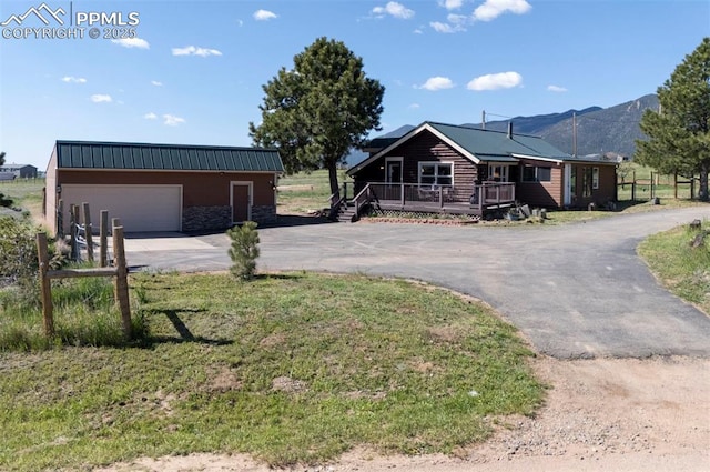 3645 Doolittle Rd, Monument, CO 80132 - view of front of property with asphalt driveway, an outdoor structure, metal roof, a deck with mountain view, and a front lawn