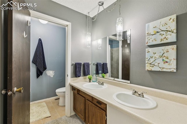 bathroom with tile patterned floors, toilet, double vanity, and a shower