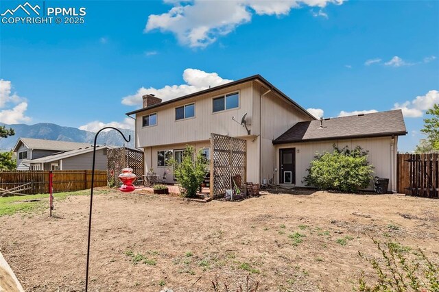 rear view of house featuring a chimney, a fenced backyard, and a mountain view