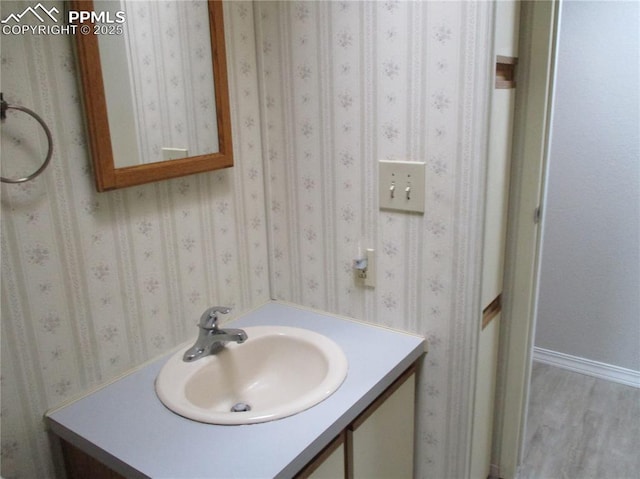 bathroom featuring vanity, wood finished floors, and baseboards