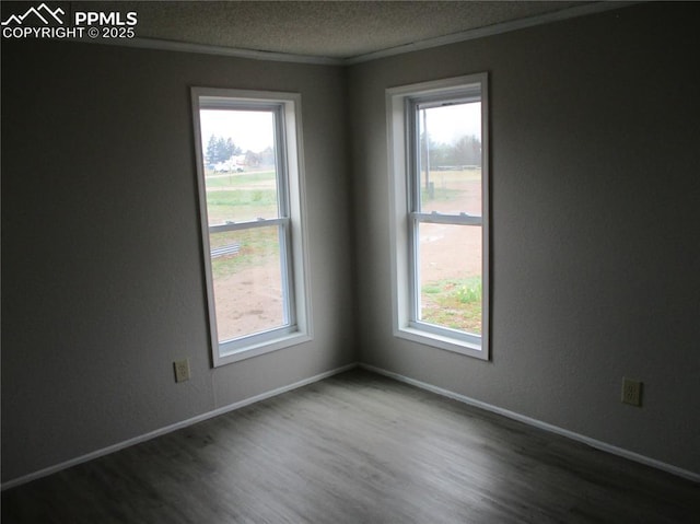 unfurnished room featuring plenty of natural light, dark wood-style floors, ornamental molding, a textured ceiling, and baseboards