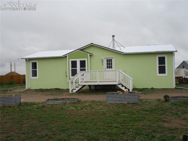 back of property featuring a wooden deck, stairway, and metal roof