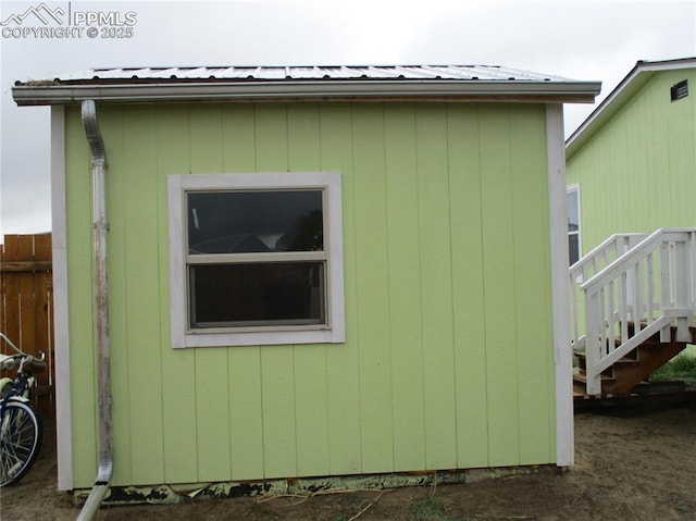 view of side of home with stairs, metal roof, and an outdoor structure
