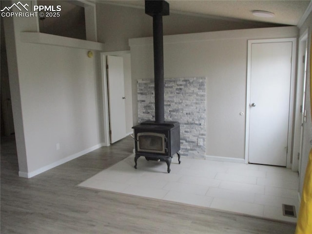 living area with a wood stove, baseboards, and wood finished floors
