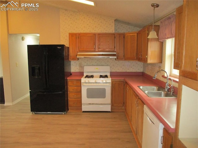 kitchen featuring white appliances, vaulted ceiling, a sink, under cabinet range hood, and brown cabinets