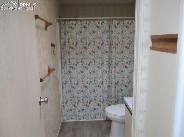 full bathroom with curtained shower, wood finished floors, toilet, vanity, and wallpapered walls