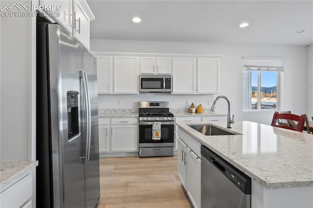 16422 Mountain Flax Dr, Monument, CO 80132 - kitchen featuring appliances with stainless steel finishes, white cabinets, light wood-style floors, an island with sink, and recessed lighting