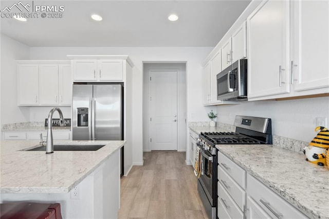 16422 Mountain Flax Dr, Monument, CO 80132 - kitchen with stainless steel appliances, white cabinets, recessed lighting, light wood-style flooring, and light stone counters