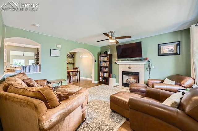 4258 Grassy Ct, Colorado Springs, CO 80916 - living room with arched walkways, a ceiling fan, wood finished floors, a fireplace, and baseboards