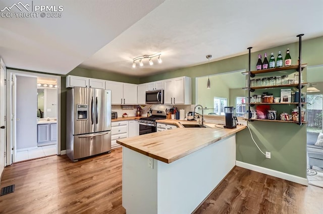 4258 Grassy Ct, Colorado Springs, CO 80916 - kitchen featuring appliances with stainless steel finishes, a sink, butcher block counters, a peninsula, and dark wood finished floors