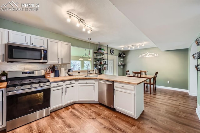 4258 Grassy Ct, Colorado Springs, CO 80916 - kitchen with stainless steel appliances, wooden counters, a sink, a peninsula, and light wood finished floors