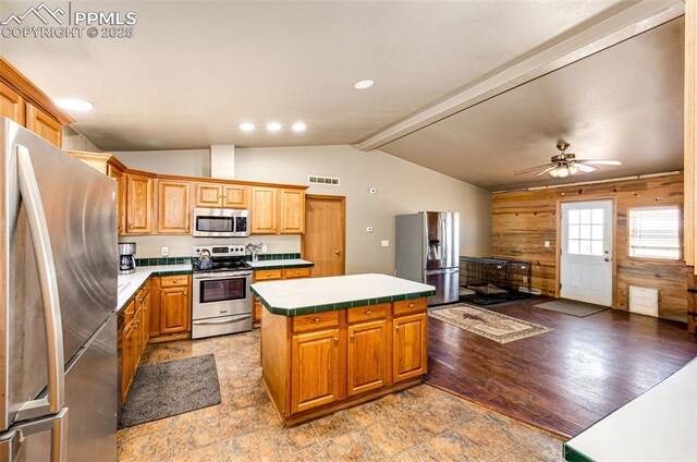 26985 Flower Cir, Simla, CO 80835 - kitchen featuring stainless steel appliances, a center island, wooden walls, a ceiling fan, and tile countertops