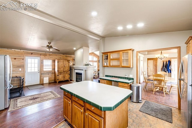 26985 Flower Cir, Simla, CO 80835 - kitchen with freestanding refrigerator, a kitchen island, a glass covered fireplace, a chandelier, and vaulted ceiling