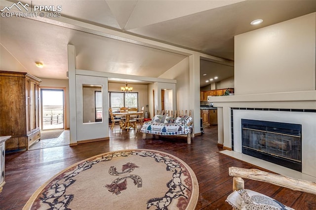 26985 Flower Cir, Simla, CO 80835 - living area featuring a chandelier, dark wood-type flooring, a fireplace, baseboards, and vaulted ceiling