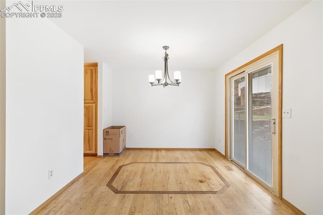 unfurnished dining area with light wood finished floors, a chandelier, and baseboards