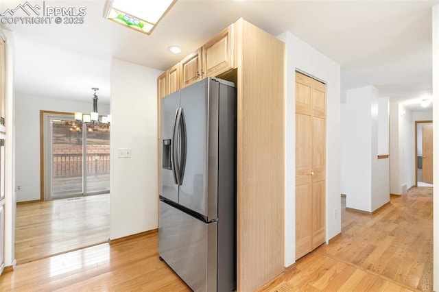 kitchen featuring stainless steel fridge with ice dispenser, light brown cabinets, light wood-type flooring, and a chandelier