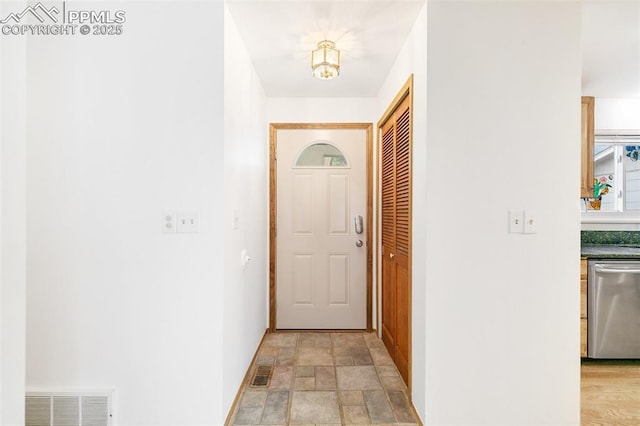 doorway featuring stone finish flooring and baseboards