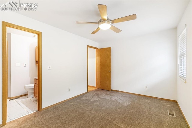 unfurnished bedroom featuring light colored carpet, baseboards, ceiling fan, and ensuite bath