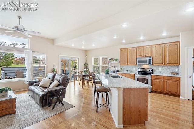 kitchen with stainless steel appliances, a sink, healthy amount of natural light, light stone countertops, and recessed lighting