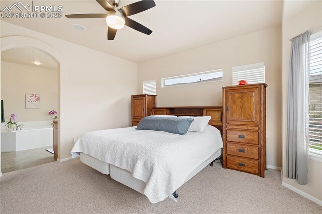 bedroom featuring light colored carpet, multiple windows, and arched walkways