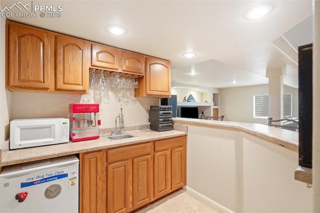 kitchen with white microwave, a sink, refrigerator, light countertops, and recessed lighting