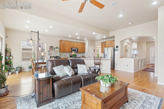 living room with arched walkways, ceiling fan, recessed lighting, light wood finished floors, and baseboards