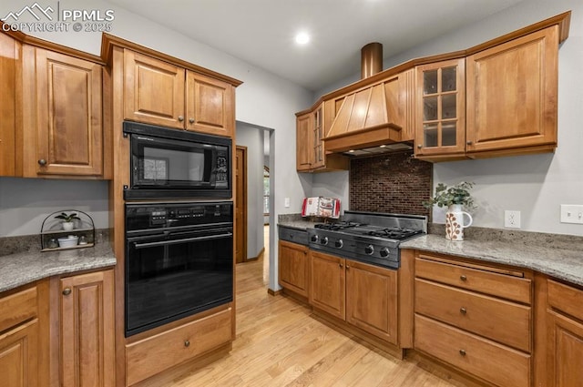 8360 Wranglers Way, Colorado Springs, CO 80908 - kitchen featuring black appliances, light wood-style flooring, glass insert cabinets, custom exhaust hood, and brown cabinets