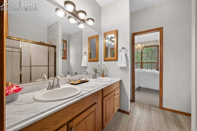 8360 Wranglers Way, Colorado Springs, CO 80908 - bathroom with wood finished floors, double vanity, baseboards, an enclosed shower, and connected bathroom